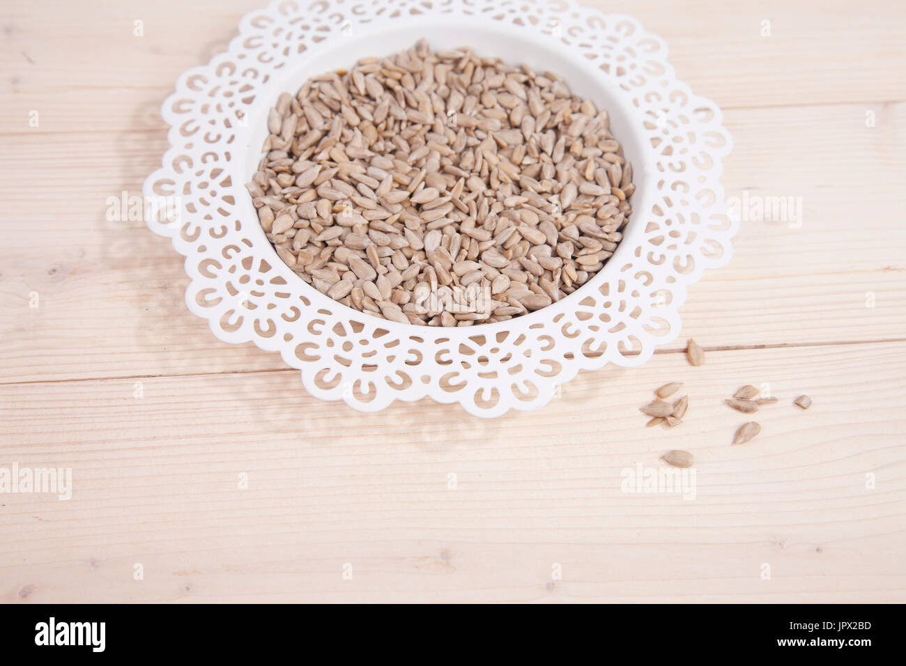 Sunflower seeds in white bowl on wooden background Stock Photo