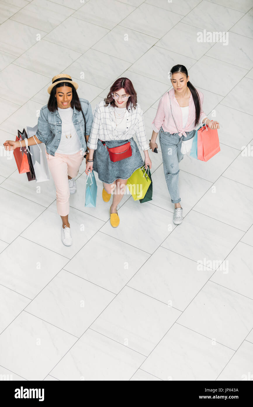 High angle view of stylish young women walking with shopping bags ...