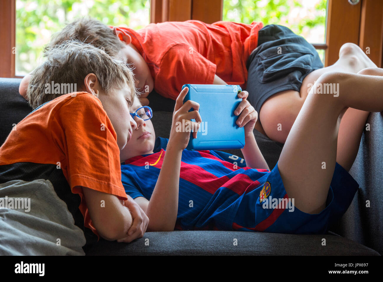 Young Boy playing computer games on iPad with other boys watching, close-up Stock Photo