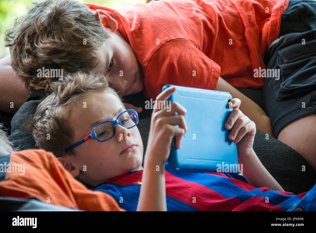 Young Boy playing computer games on iPad with other boy watching, close-up Stock Photo