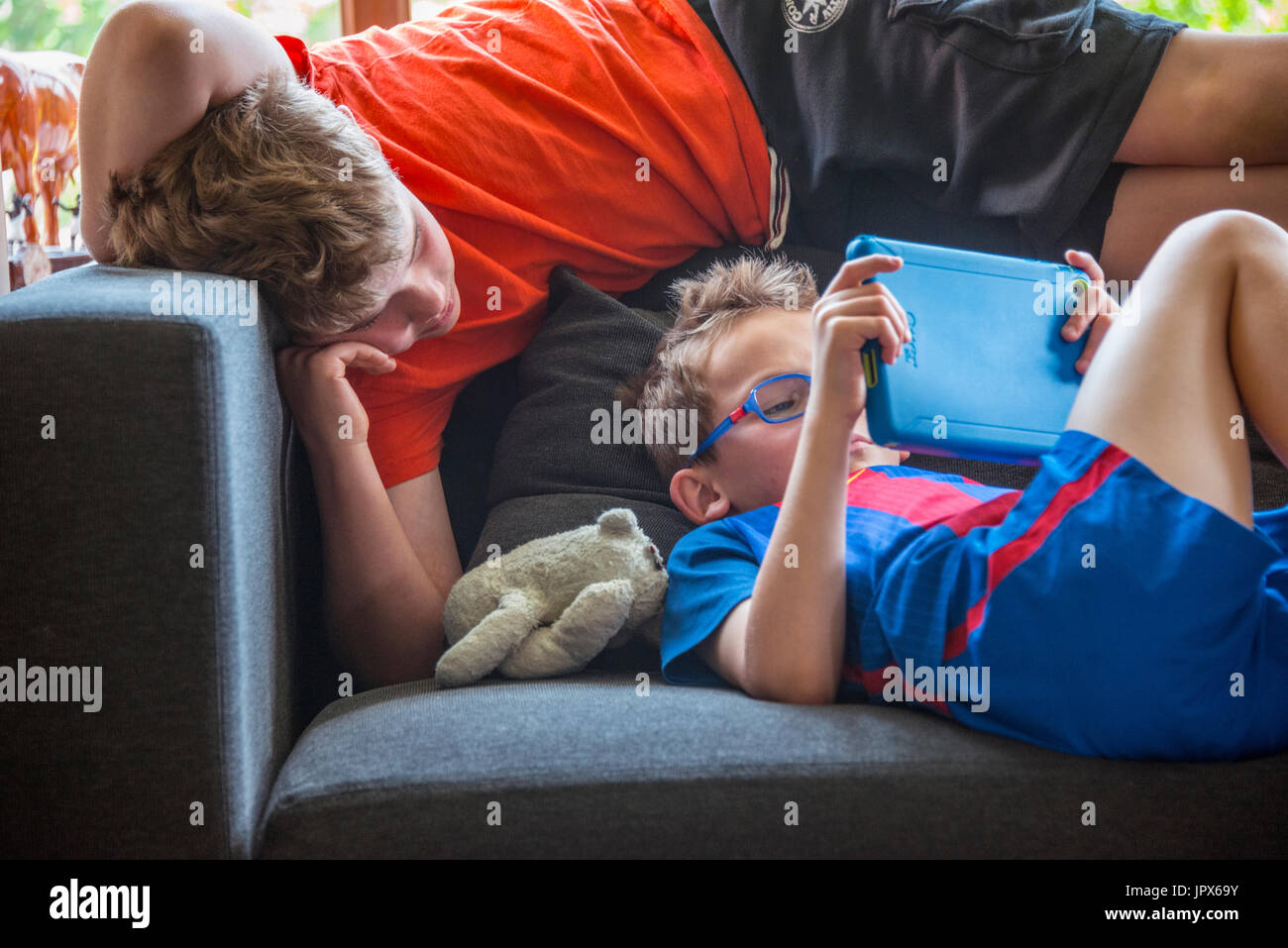 Young Boy playing Computer Game on Tablet with other boy watching Stock Photo