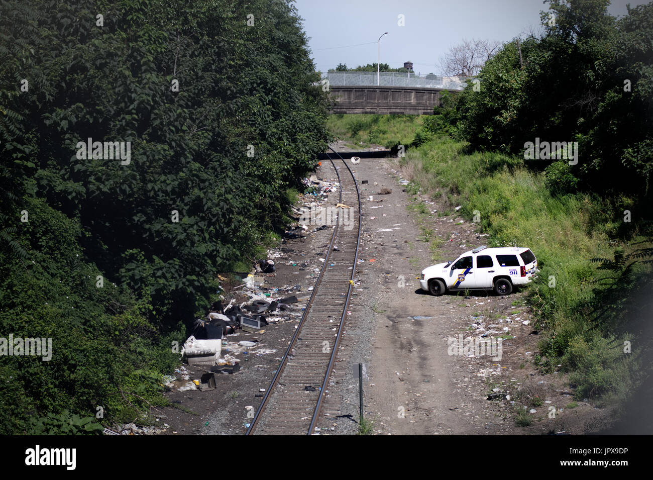 Single freight train track curves in the Fairhill/West Kensington section of Philadelphia, Pennsylvania. Thousands of used syringes, empty heroin bags Stock Photo