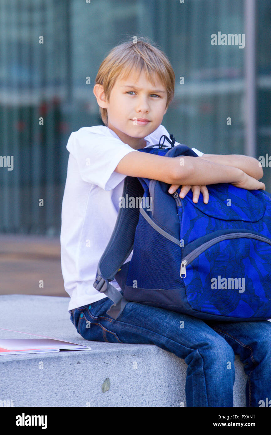 Smiling child sitting with his backpack outdoor. Education, back to ...