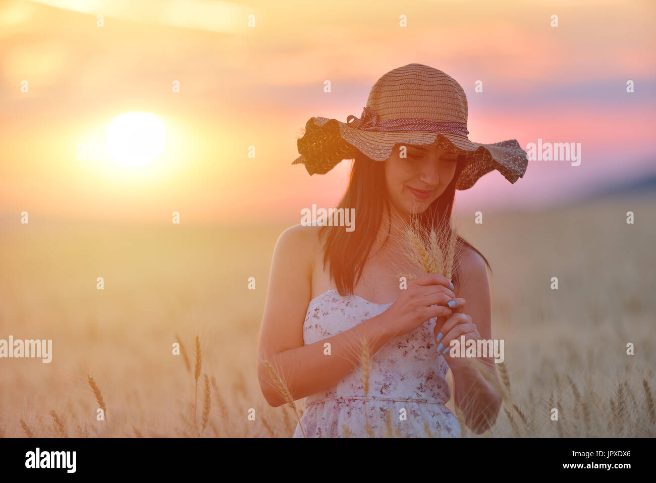 Closeup portrait of smiling young caucasian woman in wheat field. Cheerful young beautiful woman enjoying a day in natural environment at sunset Stock Photo