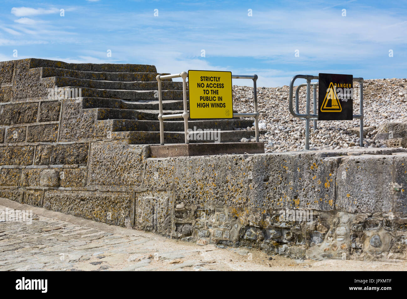 Strictly no access to the public in high winds sign and danger unguarded drop sign on steps leading to the Cobb at Lyme Regis, Dorset in July Stock Photo