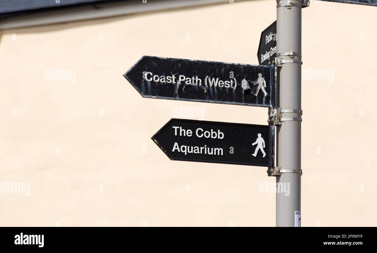 Direction signpost to The Cobb Aquarium and Coast Path (West) at Lyme Regis, Dorset UK in July Stock Photo