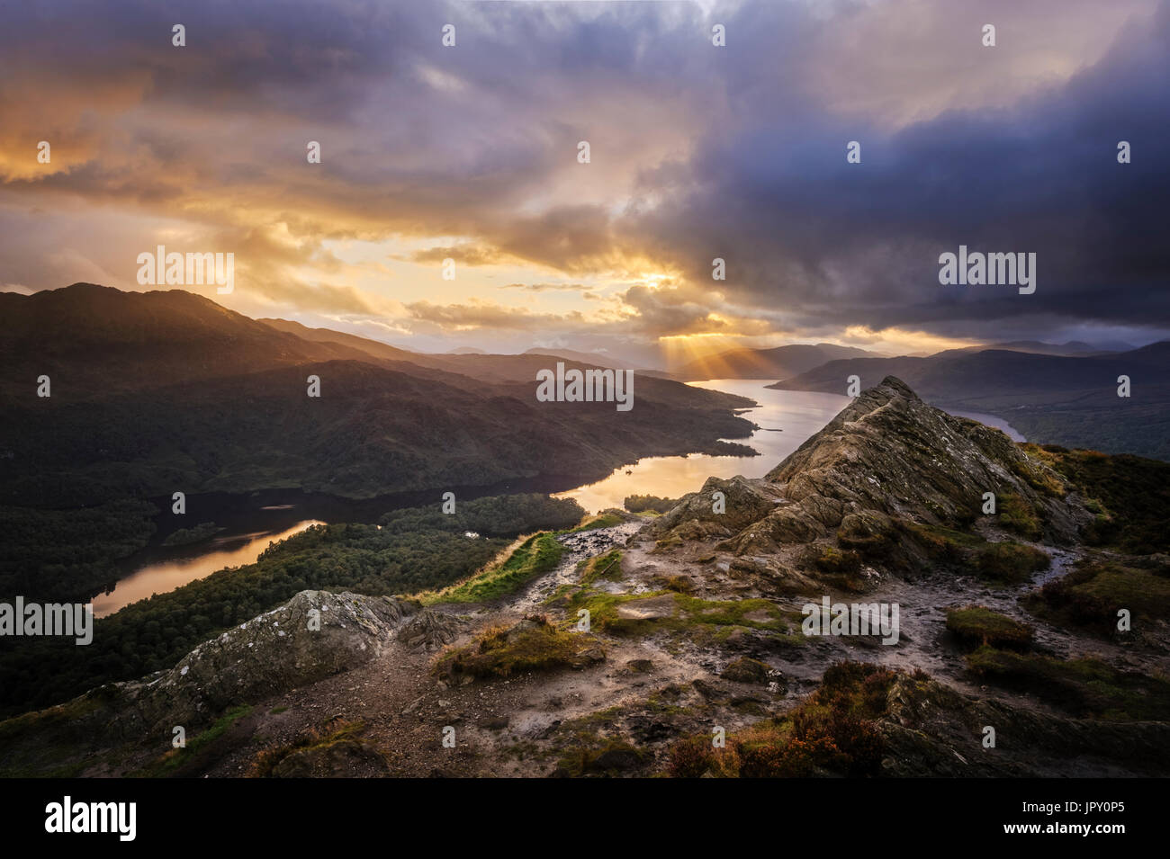 Dramatic Sunset Sky over Loch Katrine in the Trossachs in Scotland from the rocky summit of Ben A'an  a popular small mountain or hill Stock Photo