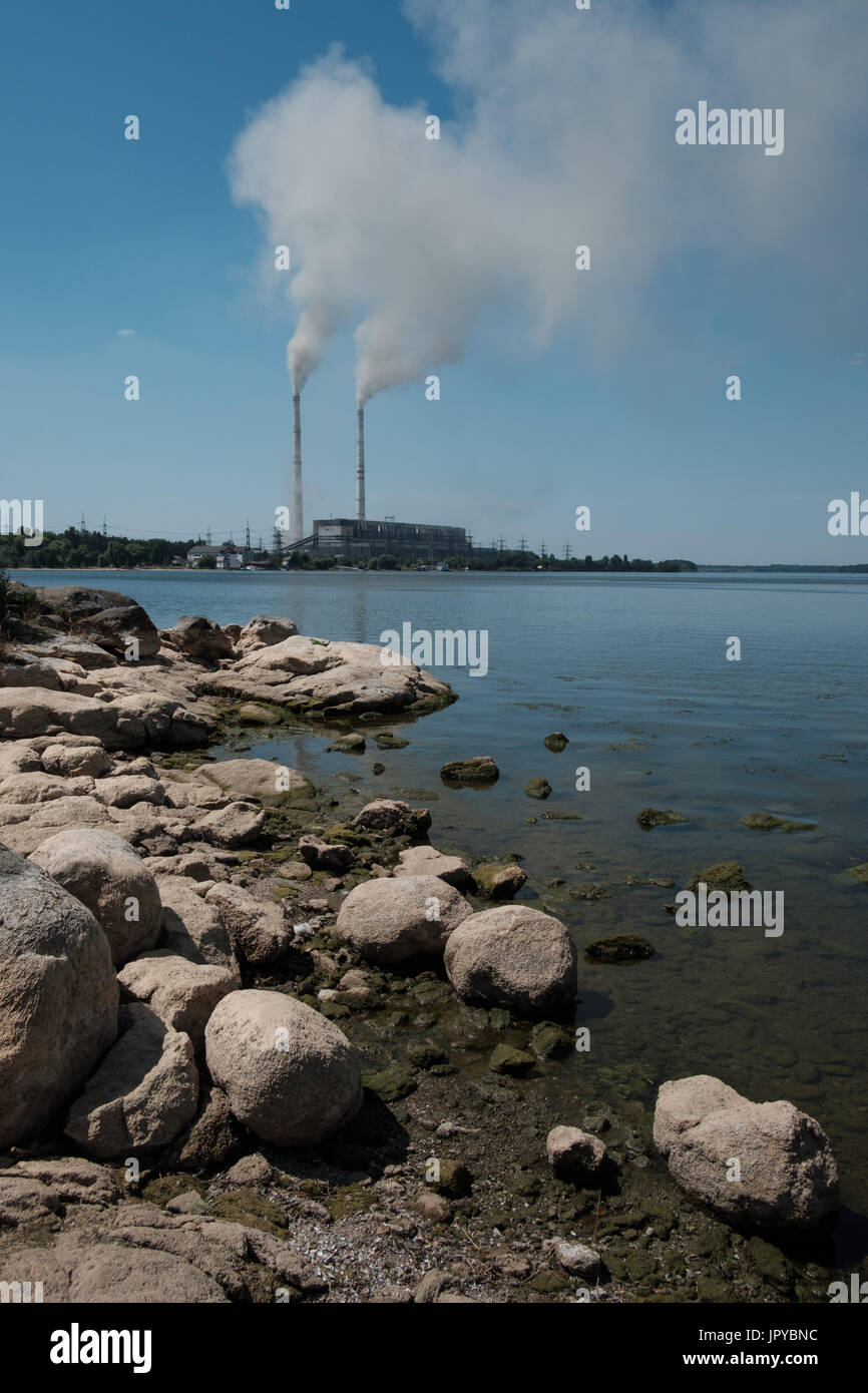 In the summer, there is very little water in the Southern Bug River near the town of Ladyzhin because of the hot weather and the enterprises take water for their needs. In the background there is a power station. Stock Photo