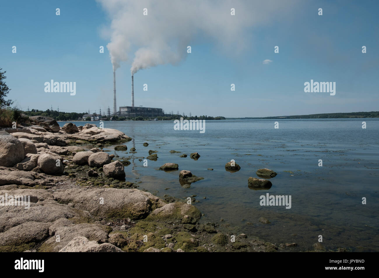 In the summer, there is very little water in the Southern Bug River near the town of Ladyzhin because of the hot weather and the enterprises take water for their needs. In the background there is a power station. Stock Photo