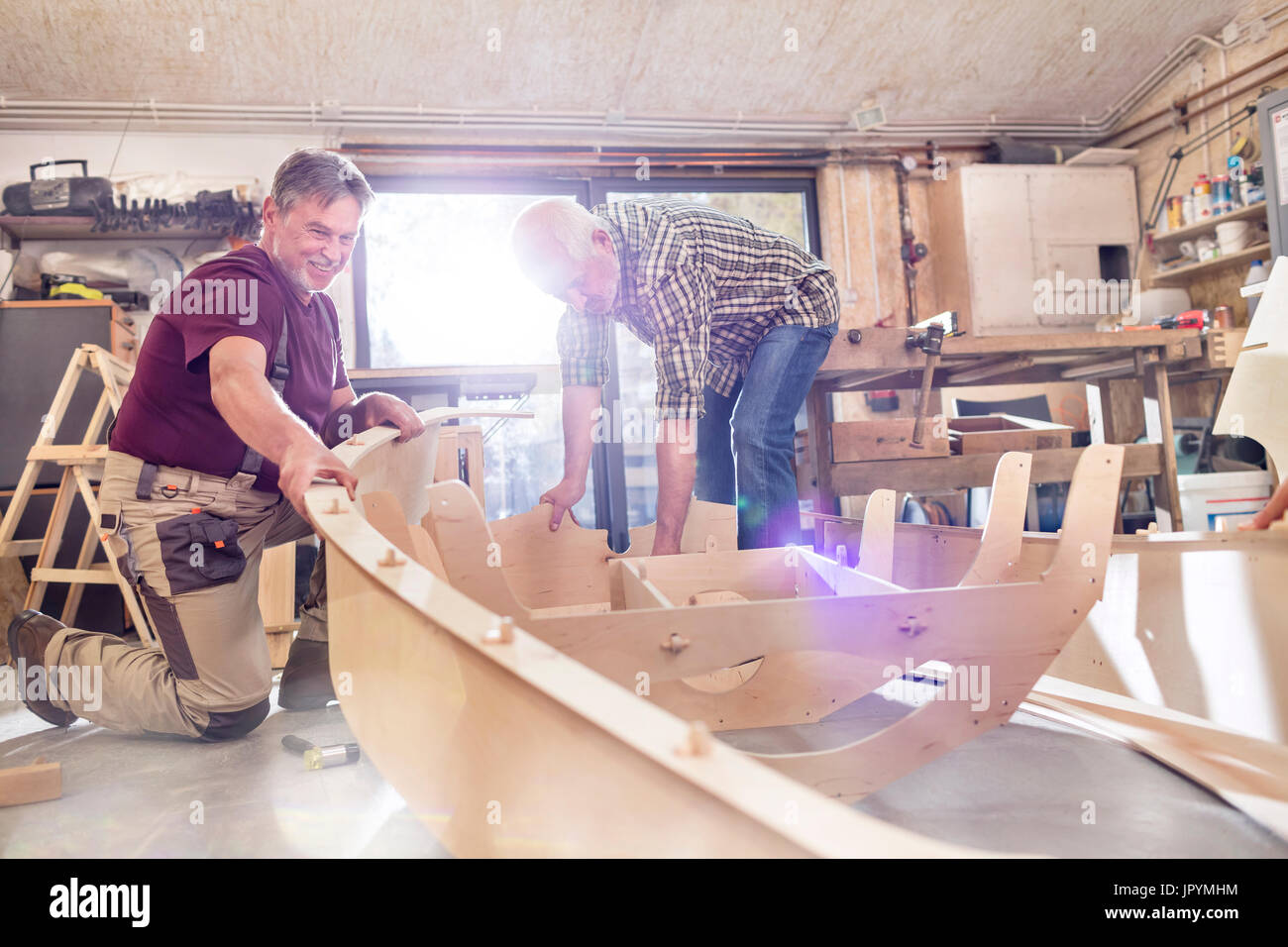 Male carpenters making wood boat in workshop Stock Photo