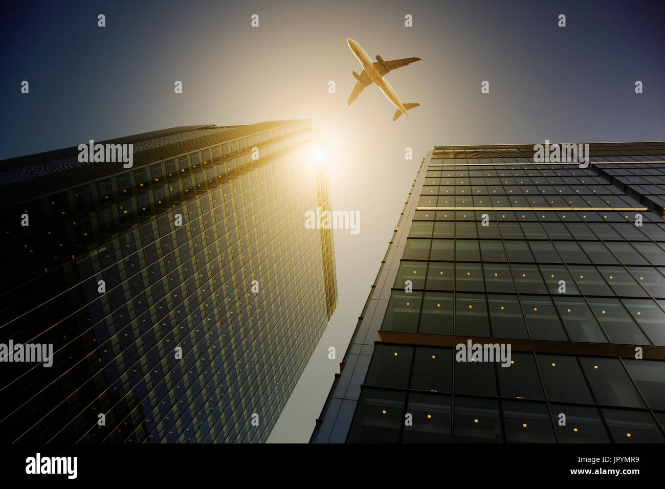 Airplane flying over highrise buildings, travel concept Stock Photo