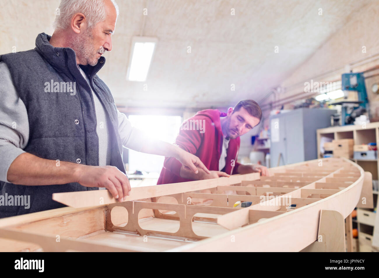 Male carpenters assembling wood boat in workshop Stock Photo