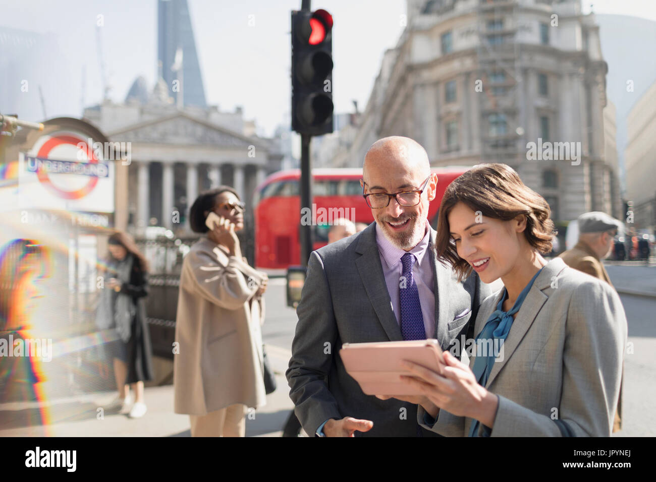 Business people using digital tablet on sunny urban city street, London, UK Stock Photo