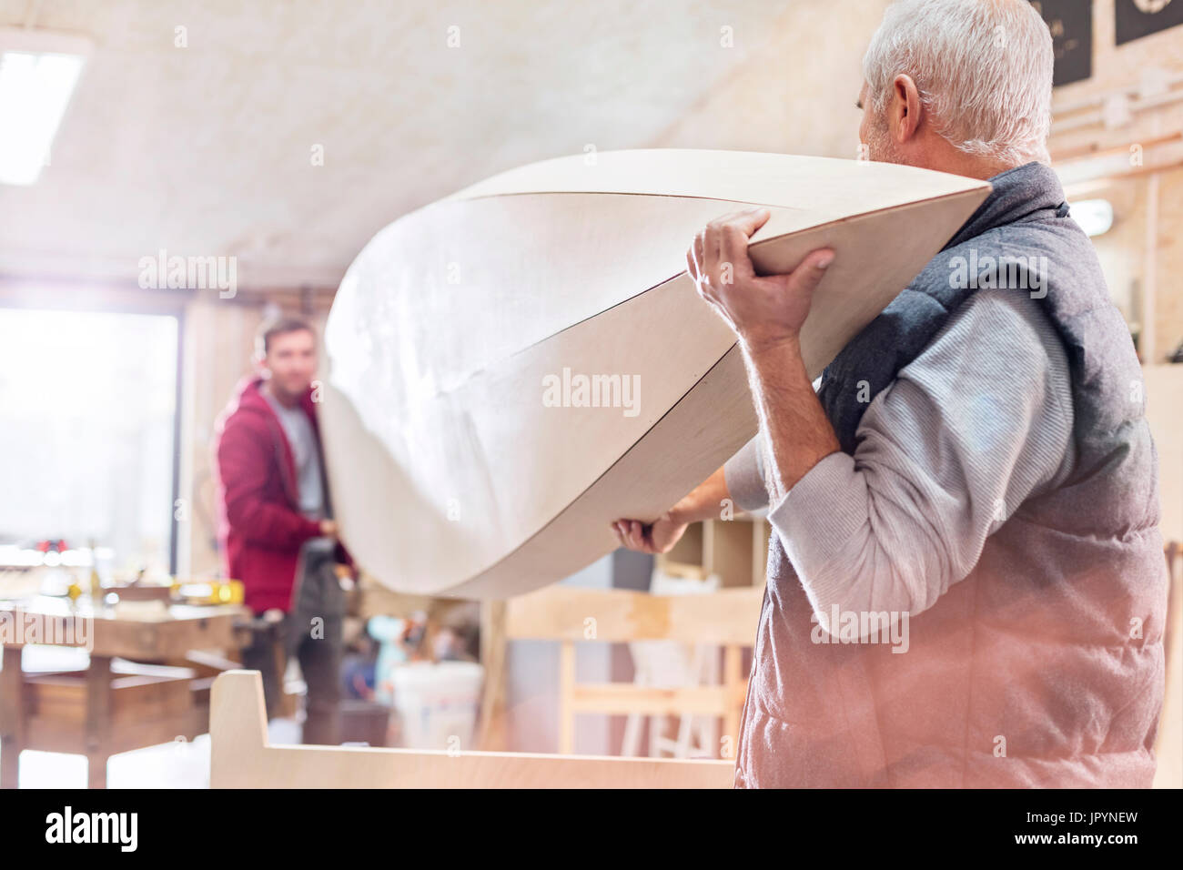 Male carpenters carrying wood boat in workshop Stock Photo