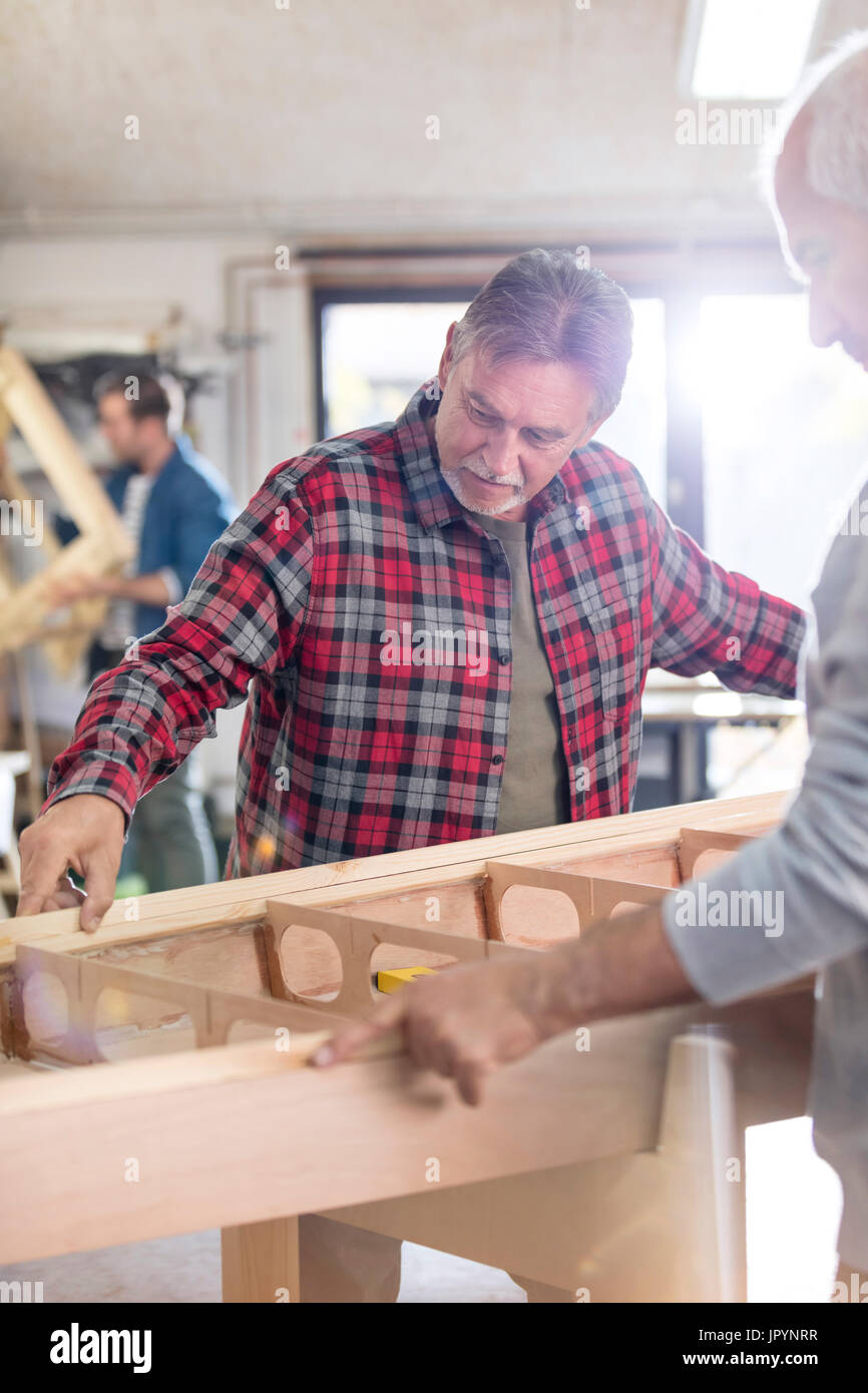 Male carpenters examining wood boat in workshop Stock Photo