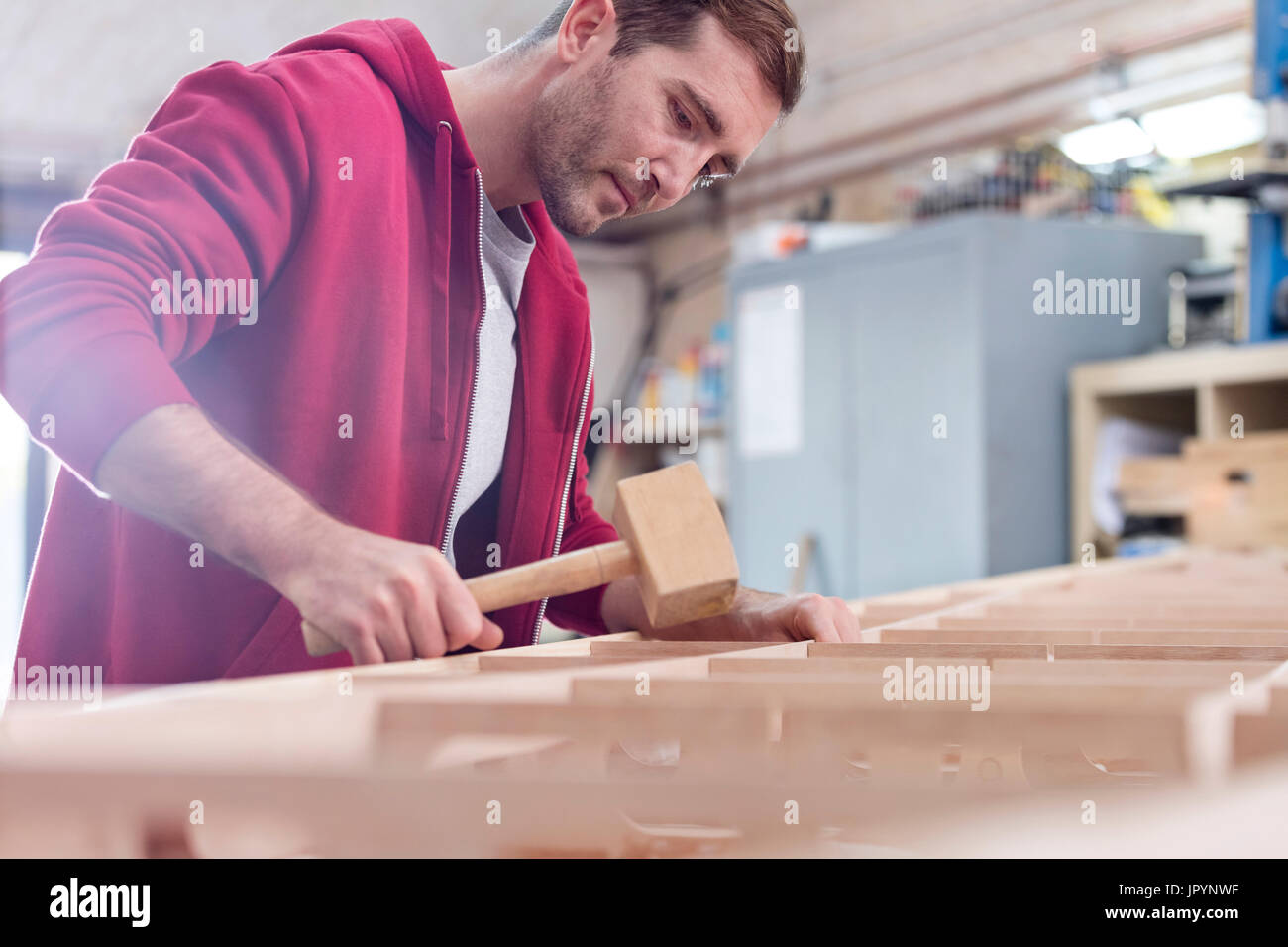 Male carpenter using wood mallet on boat in workshop Stock Photo