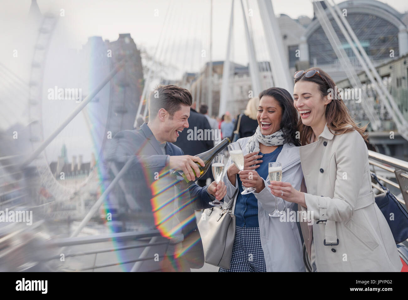 Smiling, happy friends celebrating, pouring champagne in city, London, UK Stock Photo