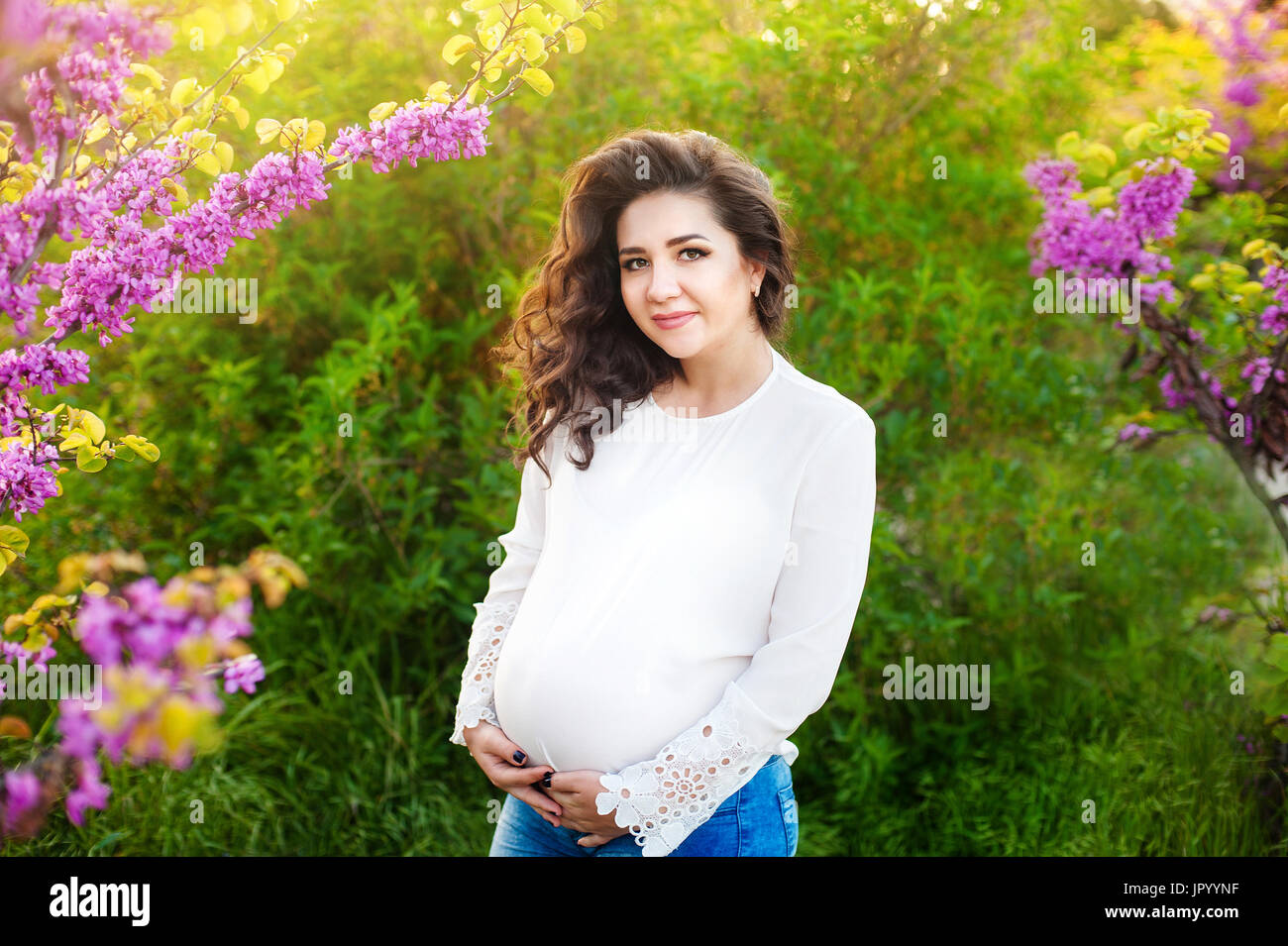 Beautiful pregnant woman hugging her belly in the park at sunset Stock ...