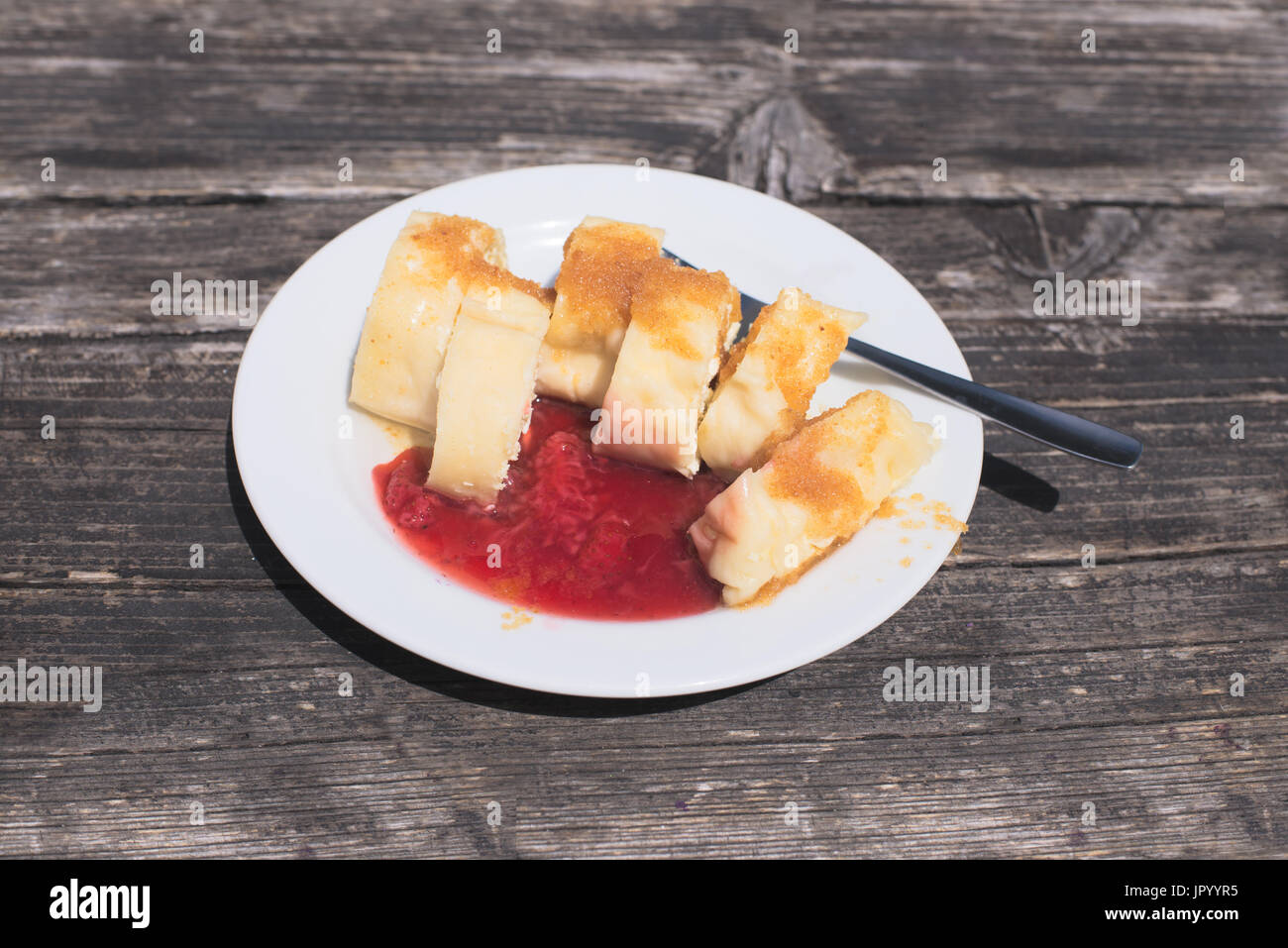 Traditional Slovene Struklji with strawberry jam an white plate, wood as background. Struklji are made of cooked dough and cottage cheese and can be s Stock Photo