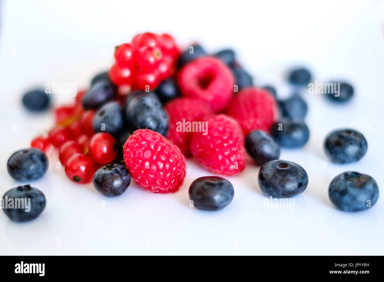 pile of mixed berries,  berry fruits on white background - rasberries, blueberries and currant Stock Photo