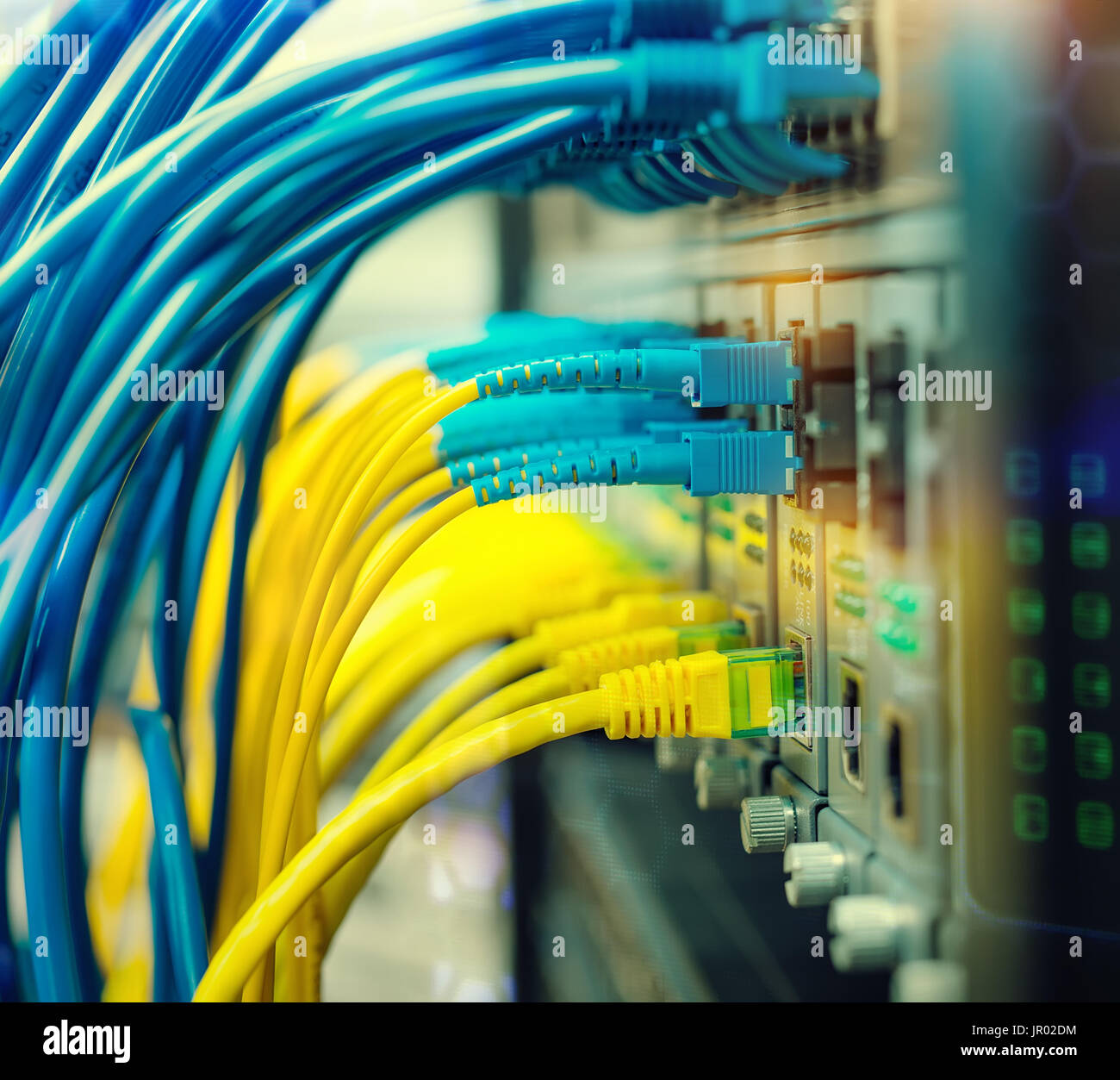 Fiber Optic cables connected to an optic ports and Network cables Stock Photo