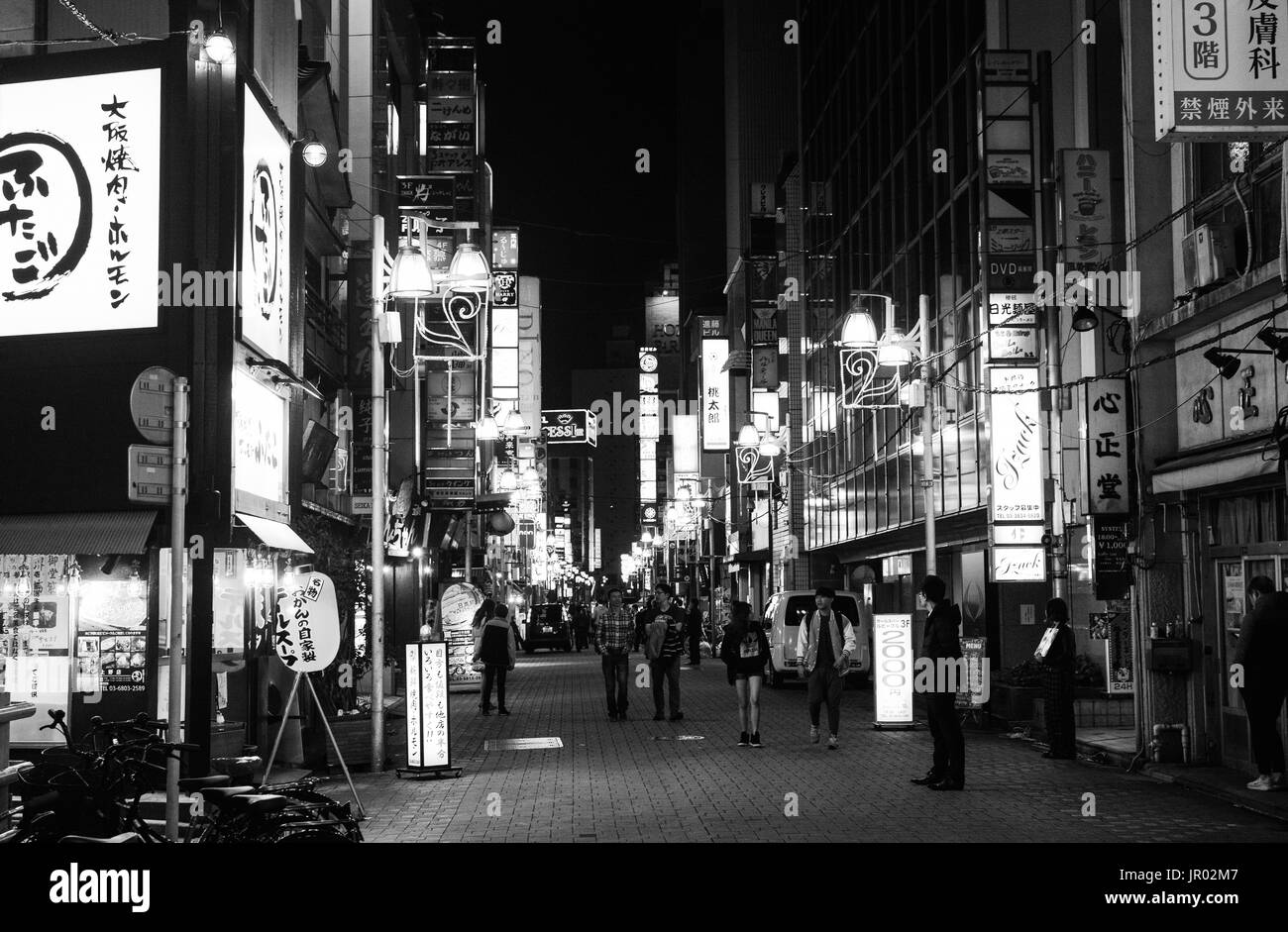 TOKYO, JAPAN - APRIL 8, 2017 - Black and white of nightlife on a busy street in Tokyo full of illuminated advertisements Stock Photo