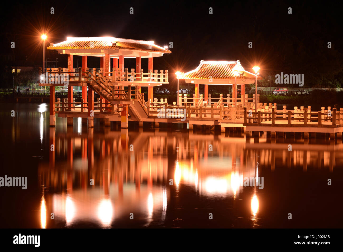 Chinese style pavilion and glowing reflection on the water of Dahu Park lake at night in Taipei, Taiwan Stock Photo
