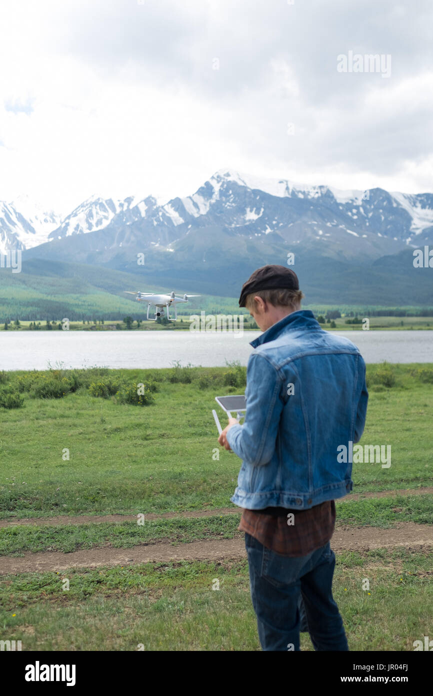 Man controling a drone on mountain background. Stock Photo