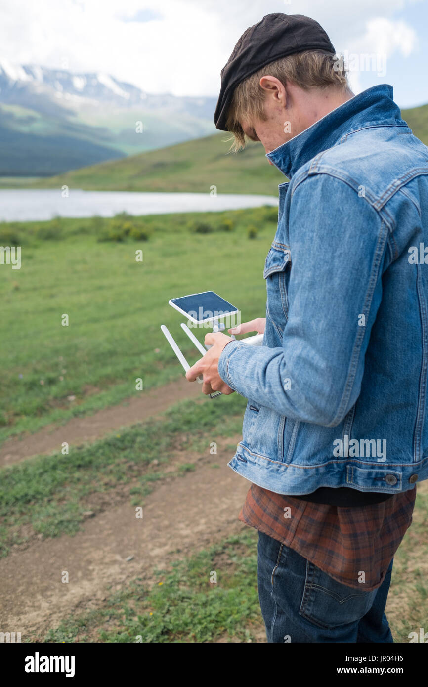 Man controling a drone on mountain background. Stock Photo