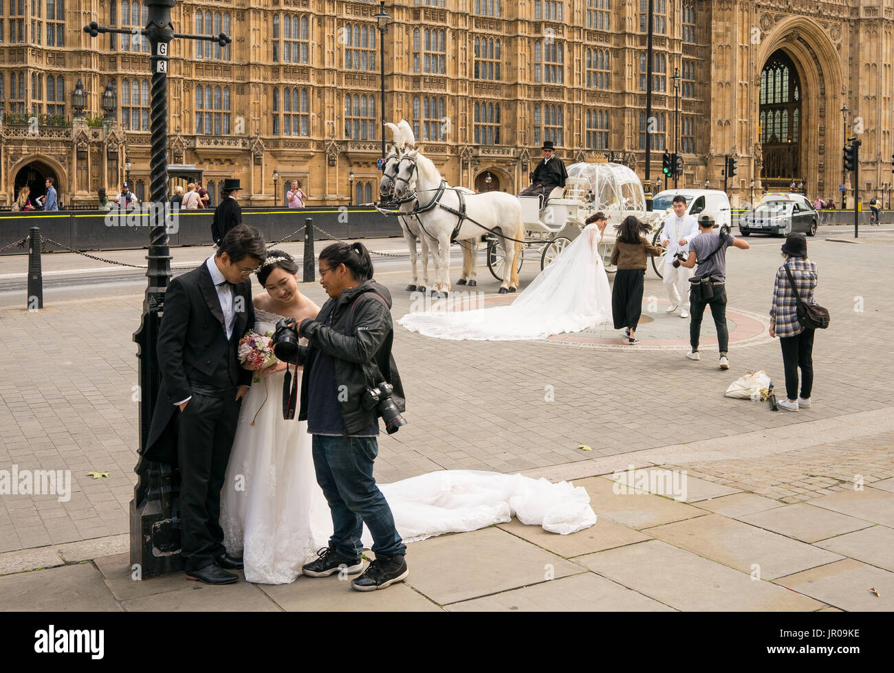 Two Chinese couples pose for wedding photographs outside the Houses of Parliament, in Westminster, London. Stock Photo