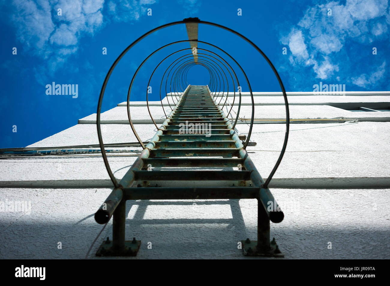 Fire escape metal ladder on a industrial building with blue sky Stock Photo