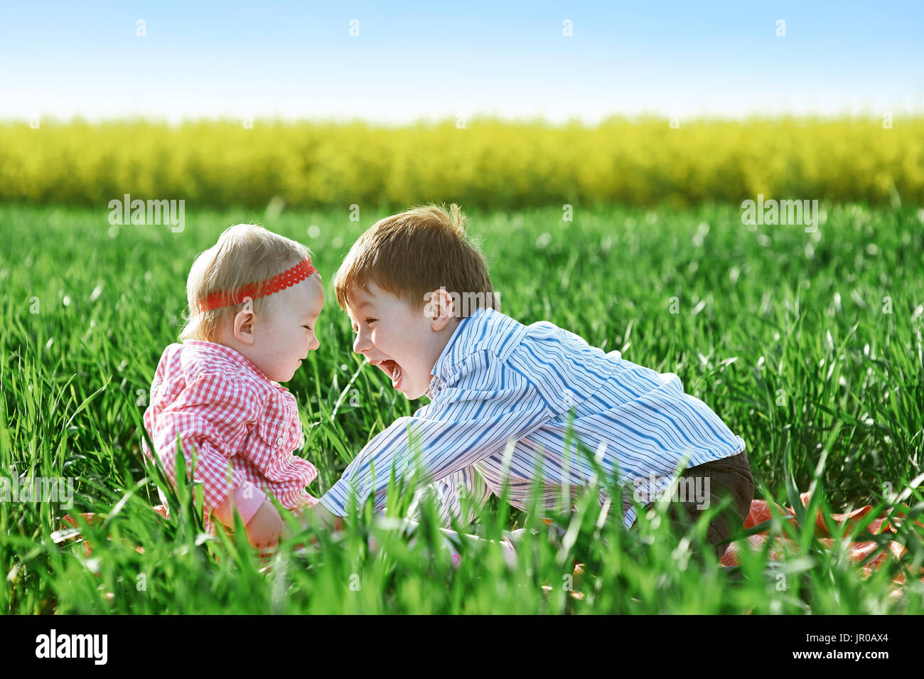 Little children boy and girl play on green grass Stock Photo