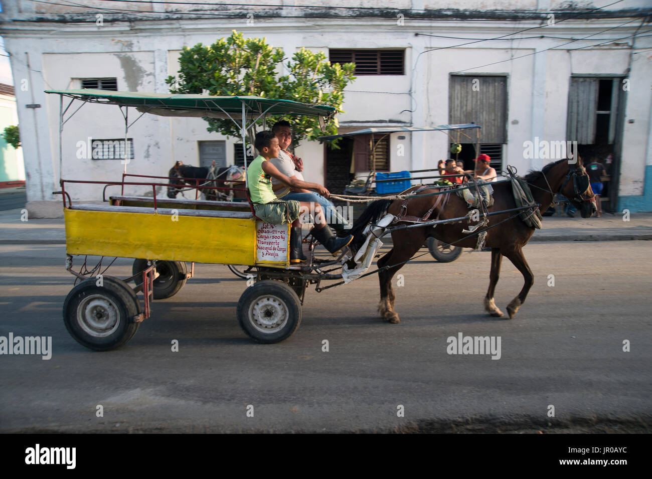 A father and son drive their horse and cart taxi through the streets of Cienfuegos Cuba Stock Photo