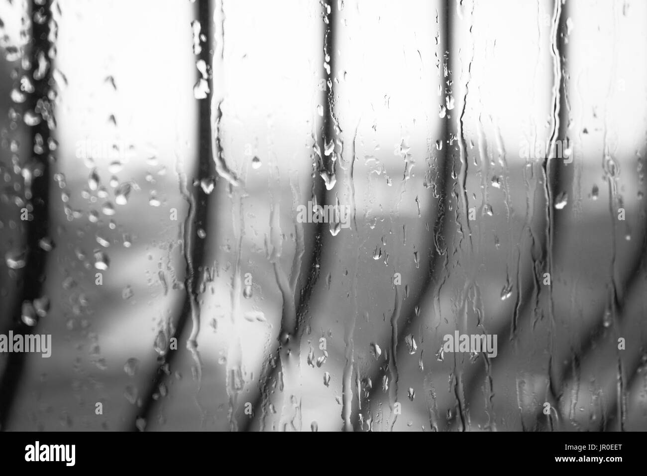 Black and white of rain falling against a window - rain concept Stock Photo