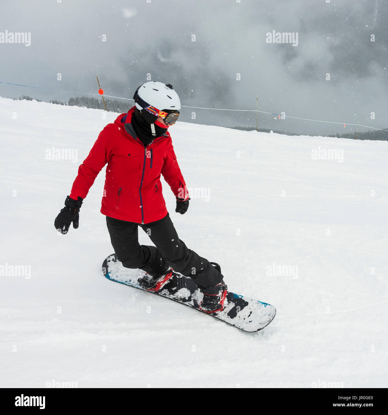 A Snowboarder In A Red Jacket Snowboarding In The Canadian Rockies; Whistler, British Columbia, Canada Stock Photo