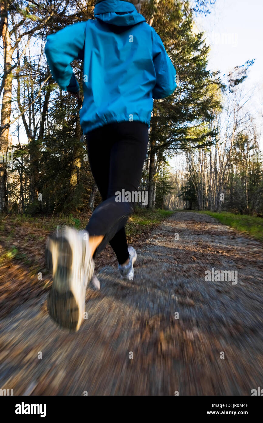 A Woman Running On A Trail In A Forest; Homer, Alaska, United States Of America Stock Photo