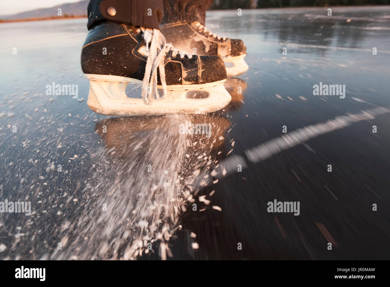 Hockey Skates Spraying Ice On A Frozen Surface; Alaska, United States