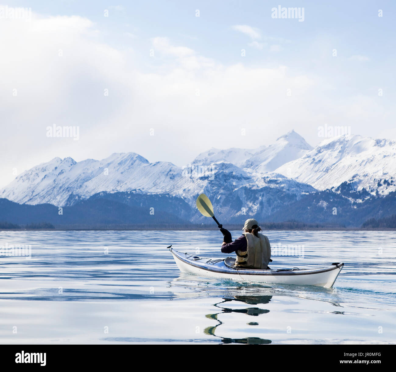 Paddling In A Canoe On Tranquil Water With A View Of The Snow Capped Kenai Mountains, Kachemak Bay State Park; Alaska, United States Of America Stock Photo