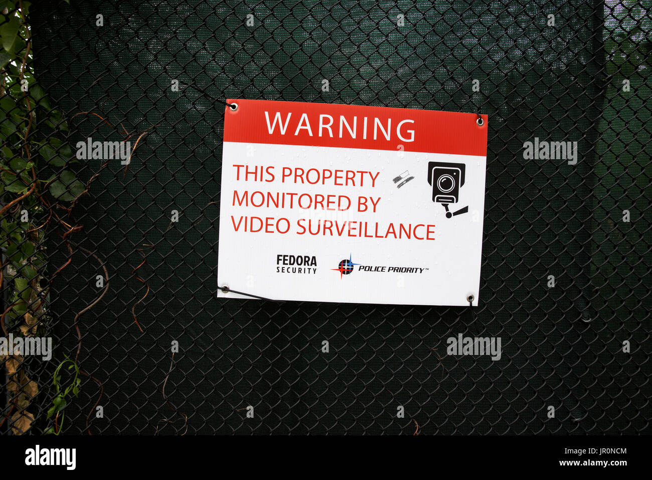 Video surveillance warning sign on fence at construction site Stock Photo