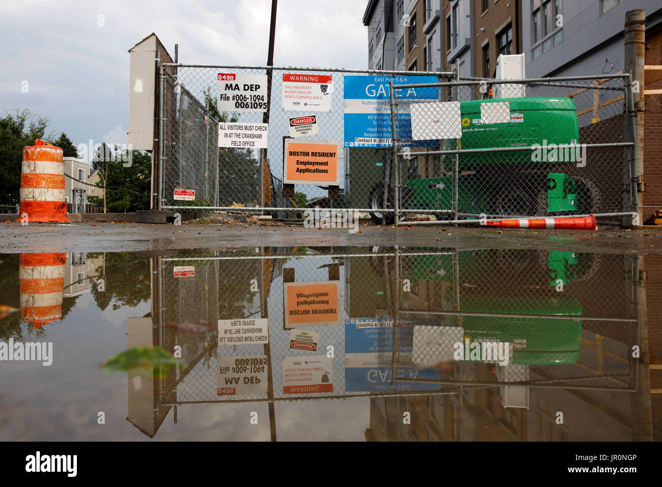 Construction site entry gate with sighs reflected in water Stock Photo