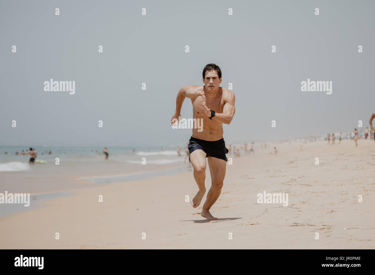 Young Man In Fitness Clothing Running Along Beach Stock Photo