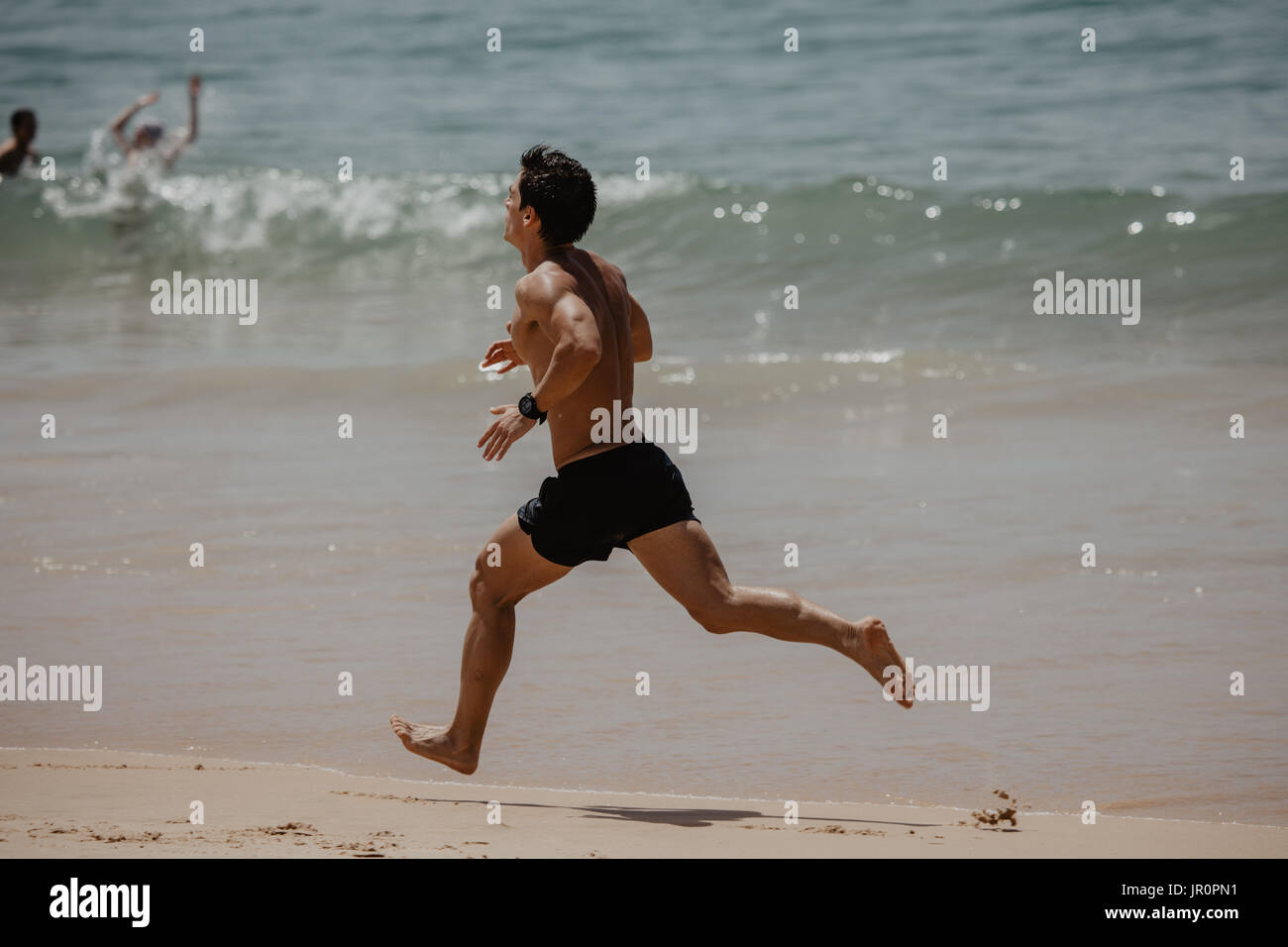 Young Man In Fitness Clothing Running Along Beach Stock Photo