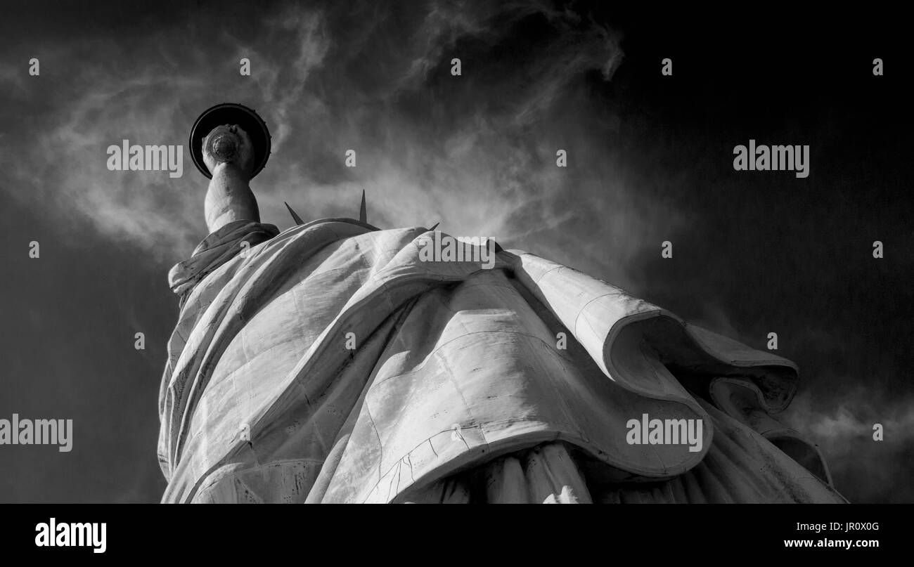 Looking up at Statue of Liberty holding the torch shining thru swirling clouds Stock Photo