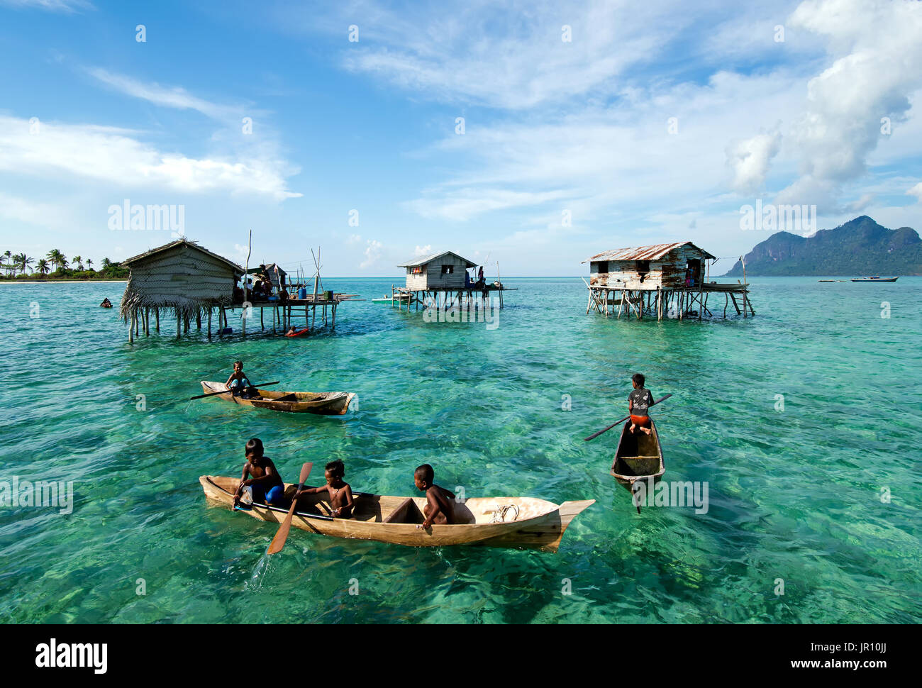 Semporna, Malaysia - 18 April, 2015: Young Bajau laut boy paddling a boat near stilted houses off the coast of Borneo in The Celebes Sea in the vicini Stock Photo