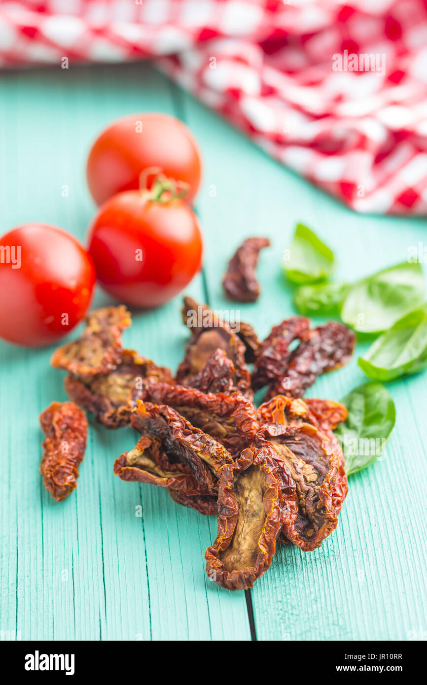 Dried sliced tomatoes and fresh tomatoes with basil leaves on colorful ...