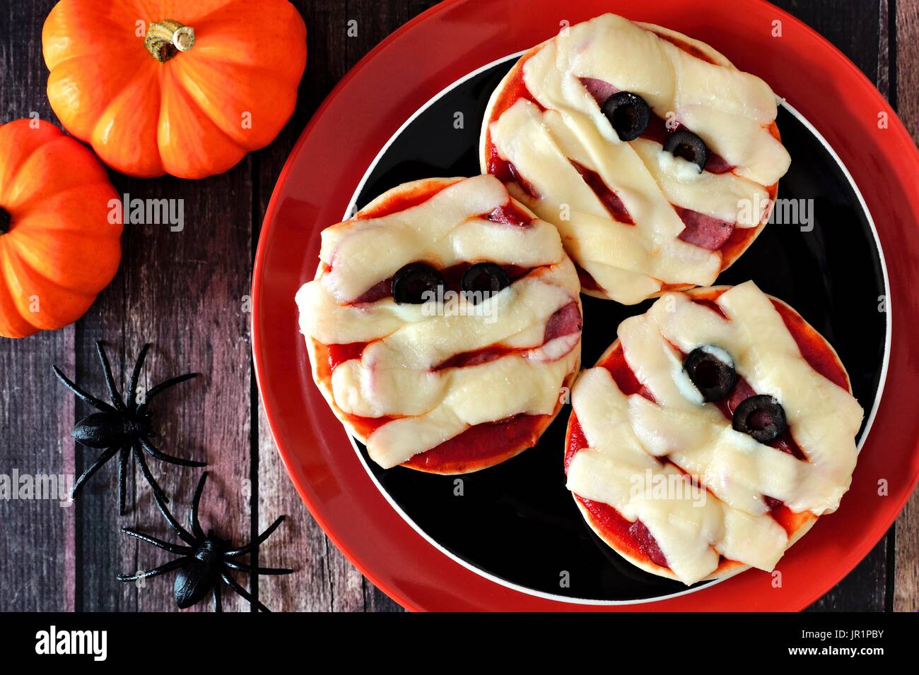 Halloween mummy mini pizzas on black and orange plate over rustic wood background Stock Photo
