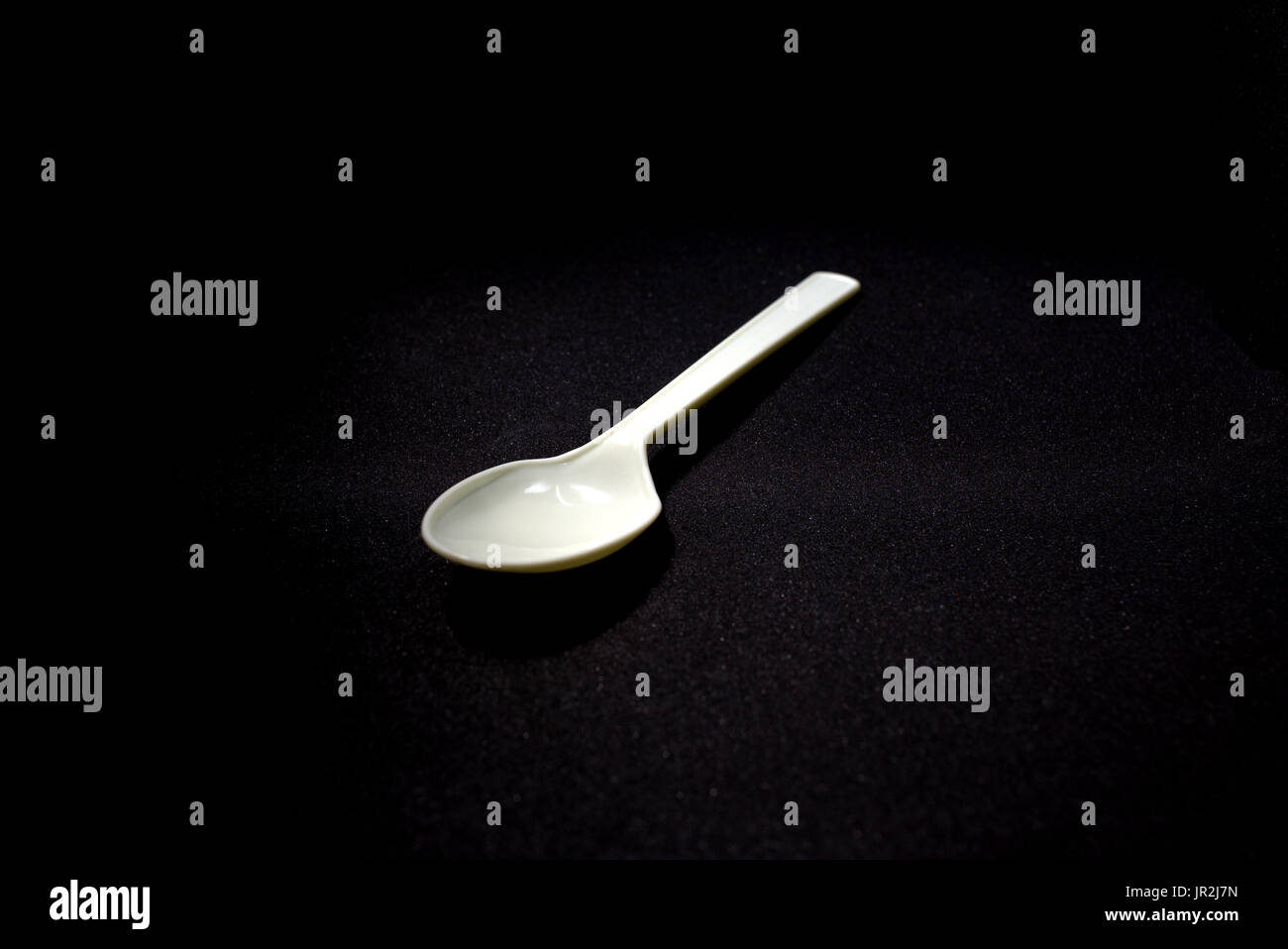 Close up still life of a simple plastic spoon.  Part of a continuing series of experimenting with improvised lighting and close-up shots Stock Photo