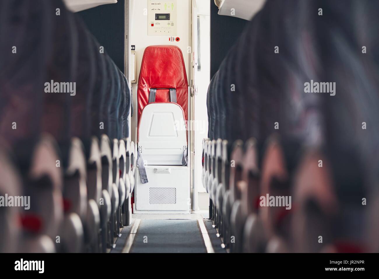 Aisle in economy class and jump seat for cabin crew in the commercial airplane. Stock Photo