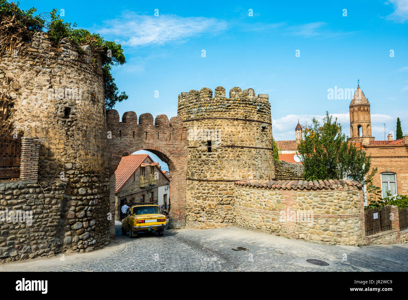 An Old Soviet Car Driving Through The Arch In The Remnants Of 18th Century Fortifications And Watchtowers; Sighnaghi, Kakheti Region, Georgia Stock Photo