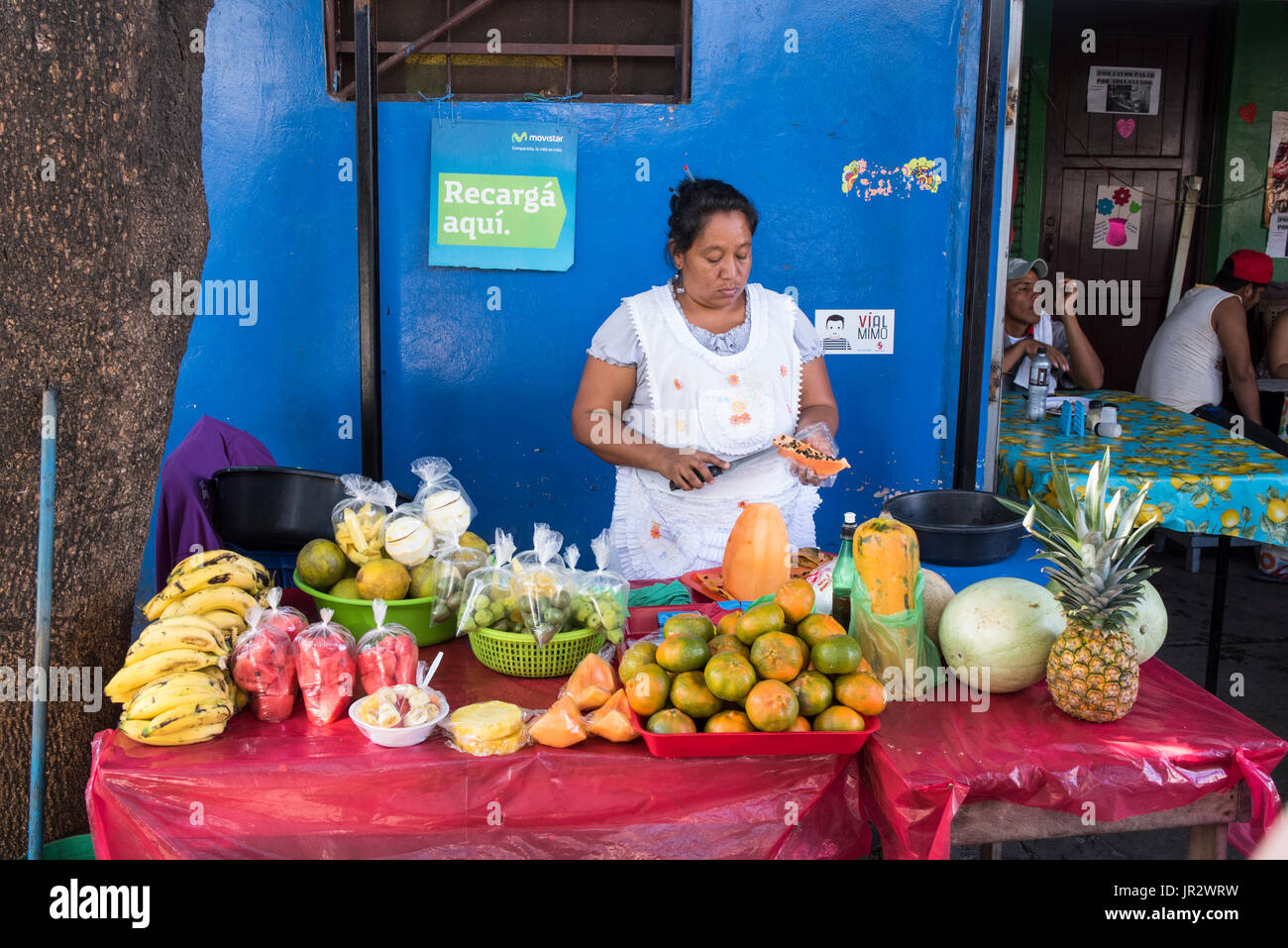 A Female Vendor Works Cutting Fruit At A Stand Selling Fresh Fruit